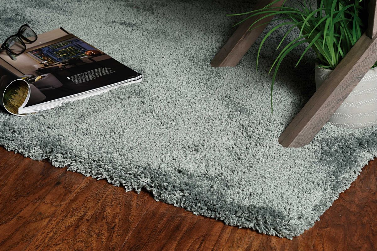 Light blue rug on a wooden floor with a magazine and glasses on top