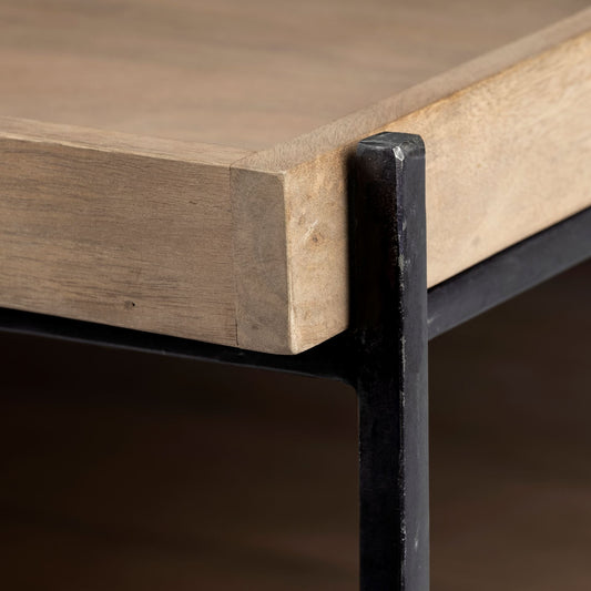 Close-up of a wooden table corner with a black metal leg on a dark background