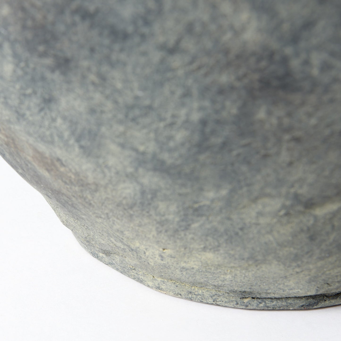 Close-up of a textured stone bowl on a white background