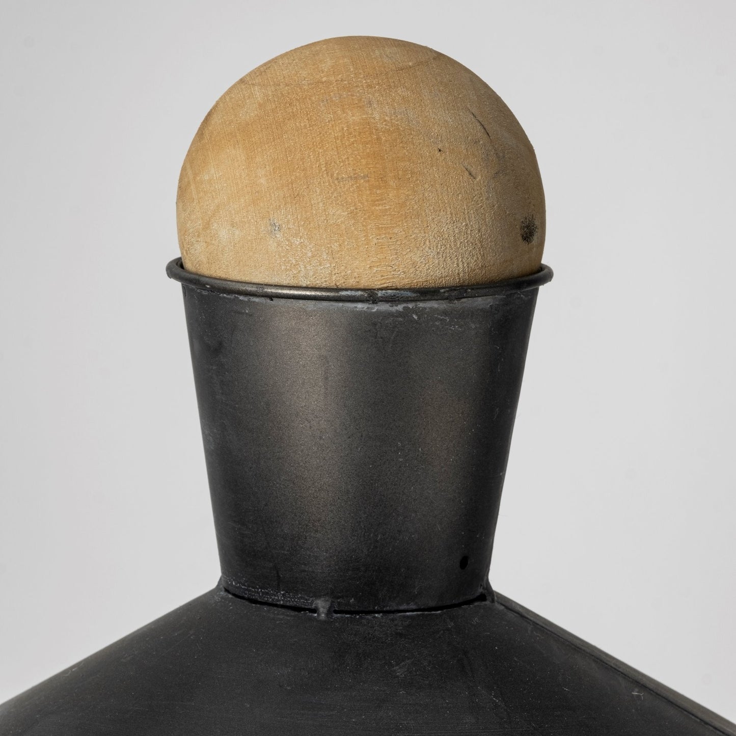 Black metal container with a wooden ball on top against a white background