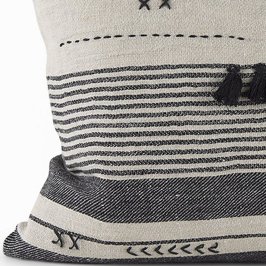 Close-up of a decorative pillow with black and white striped pattern and tassels.