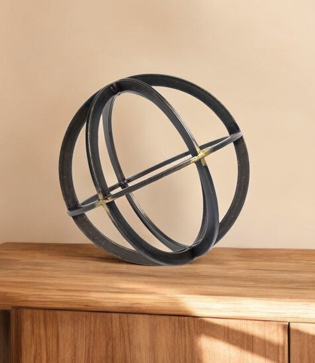 Decorative object resembling a sphere with intersecting rings on a wooden surface against a beige background