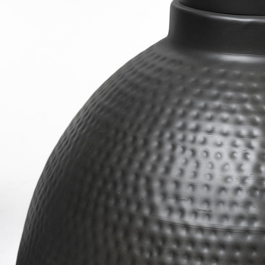 Close-up of a textured black vase on a white background
