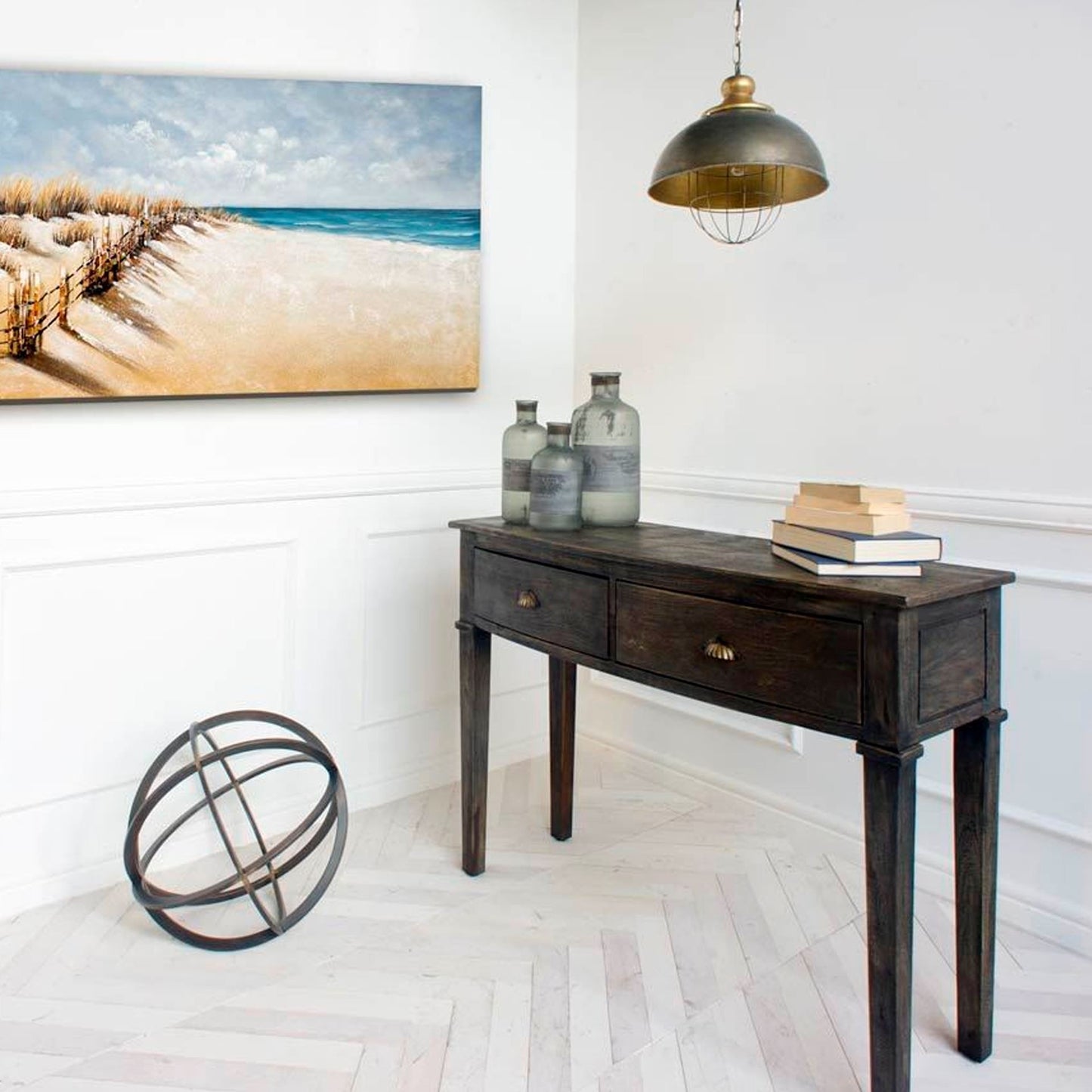Wooden console table with decorative items in a room with a beach-themed painting on the wall.