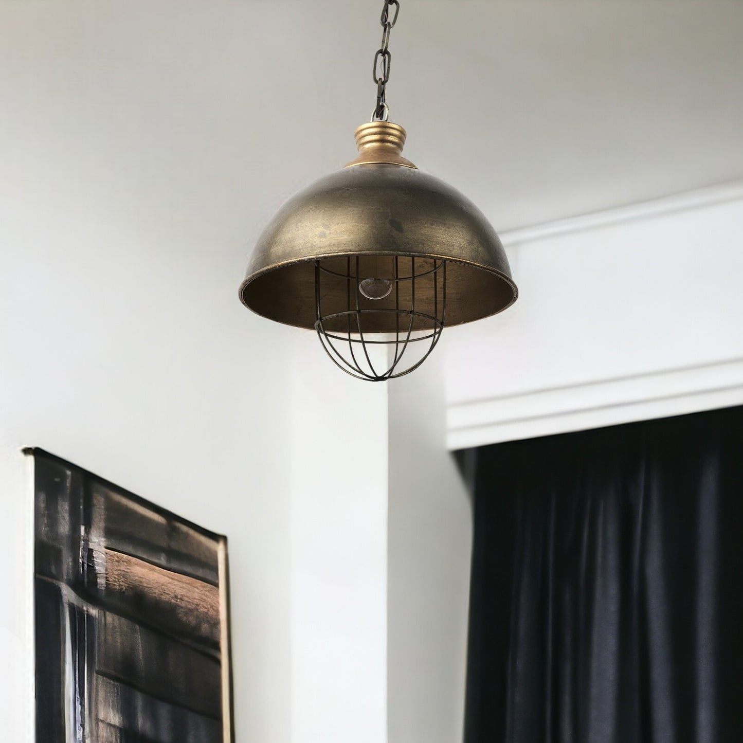 Bronze pendant light hanging in a room with a white wall and black curtain.