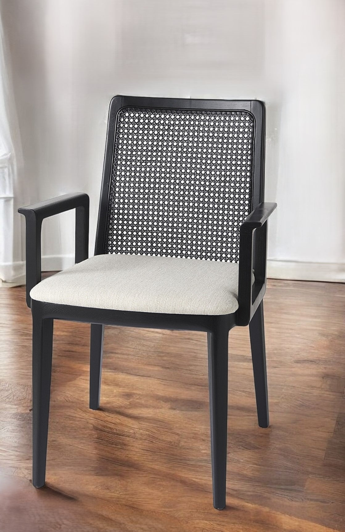 Chair with black woven backrest and white cushion on a wooden floor.