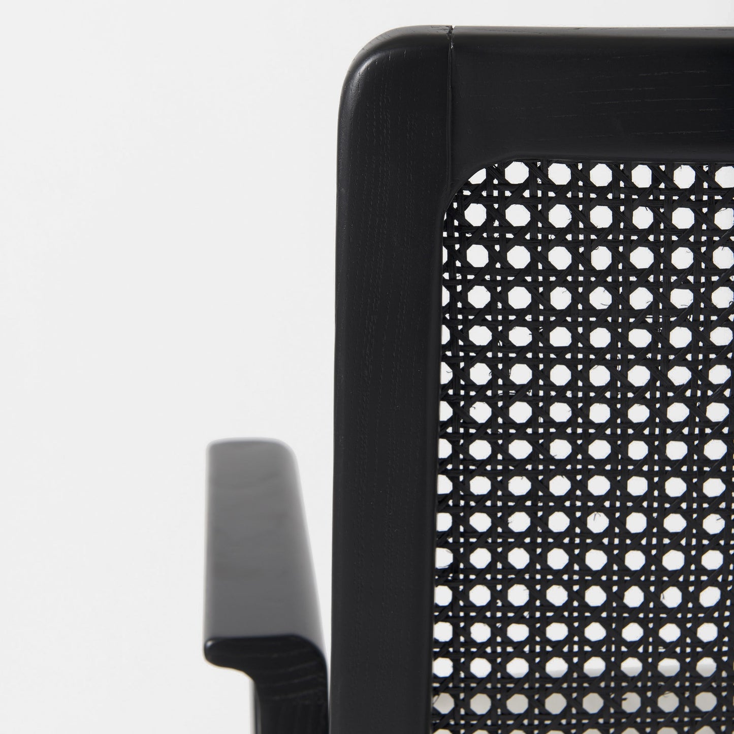 Close-up of a black office chair with a perforated backrest on a white background