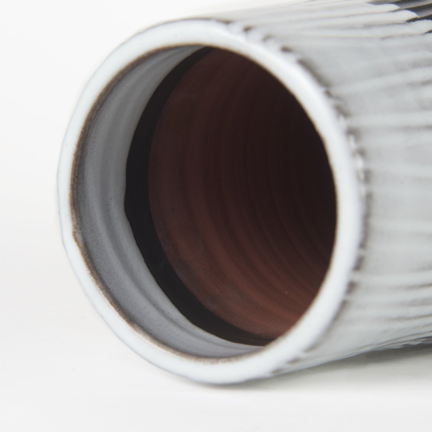 Close-up of a cylindrical vase with a textured surface on a white background