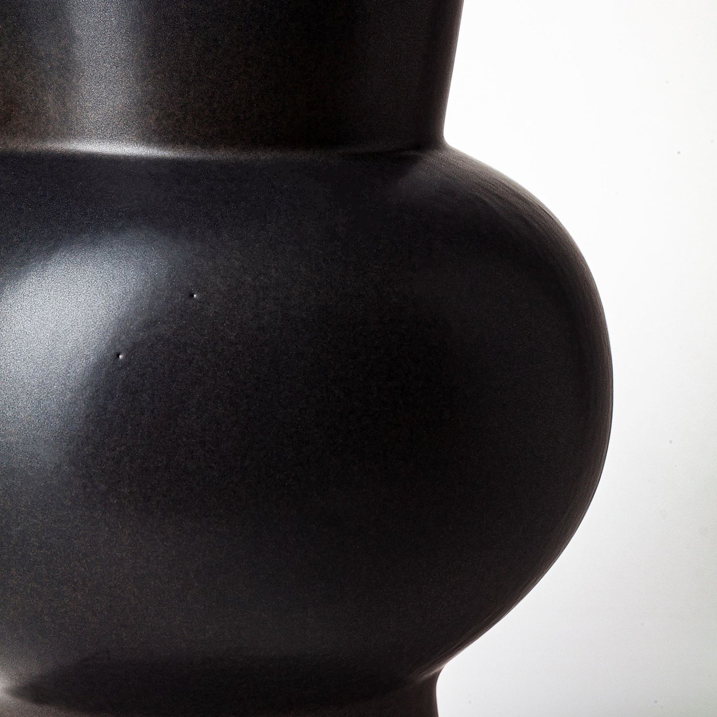 Close-up of a black ceramic vase on a white background