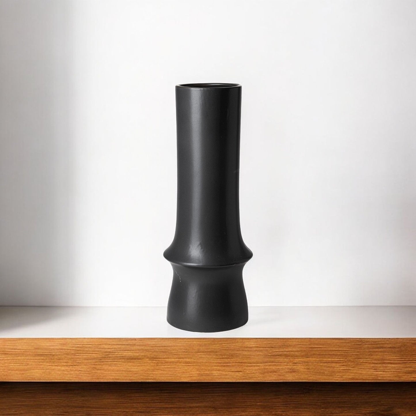 Black vase on a wooden shelf with a white background