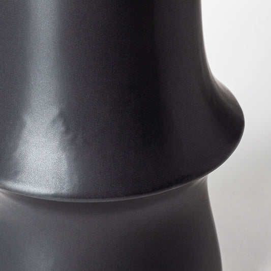 Close-up of a black ceramic vase on a light gray background