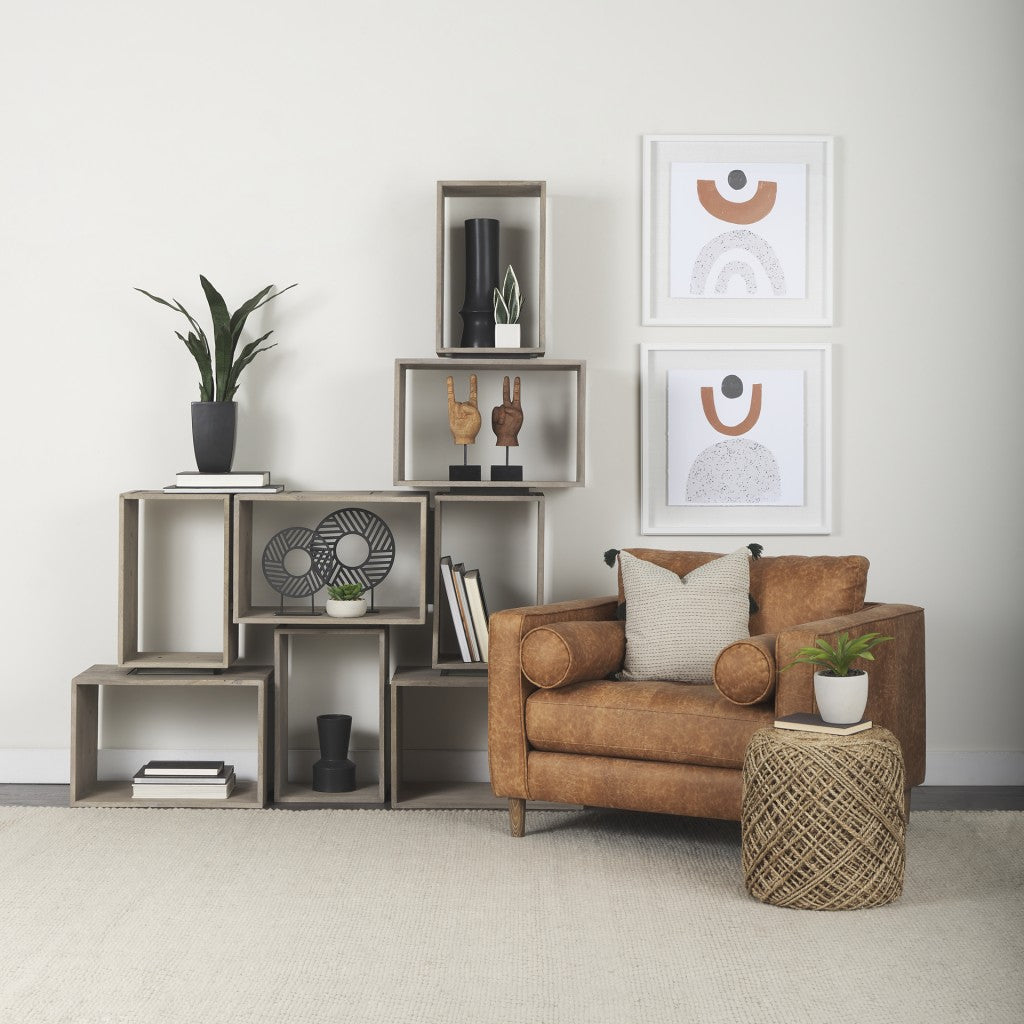 Modern living room with a brown armchair, bookshelf, and wall art.