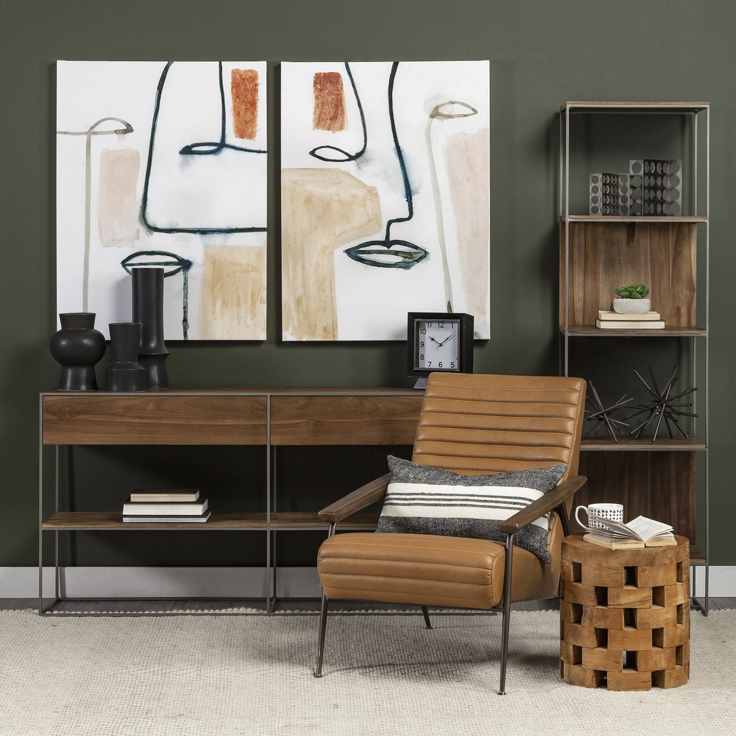 Modern interior with a brown leather chair, wooden side table, and abstract art on a dark green wall.