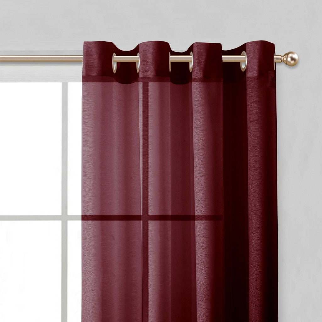 Maroon curtain with grommets on a gold rod against a light gray background