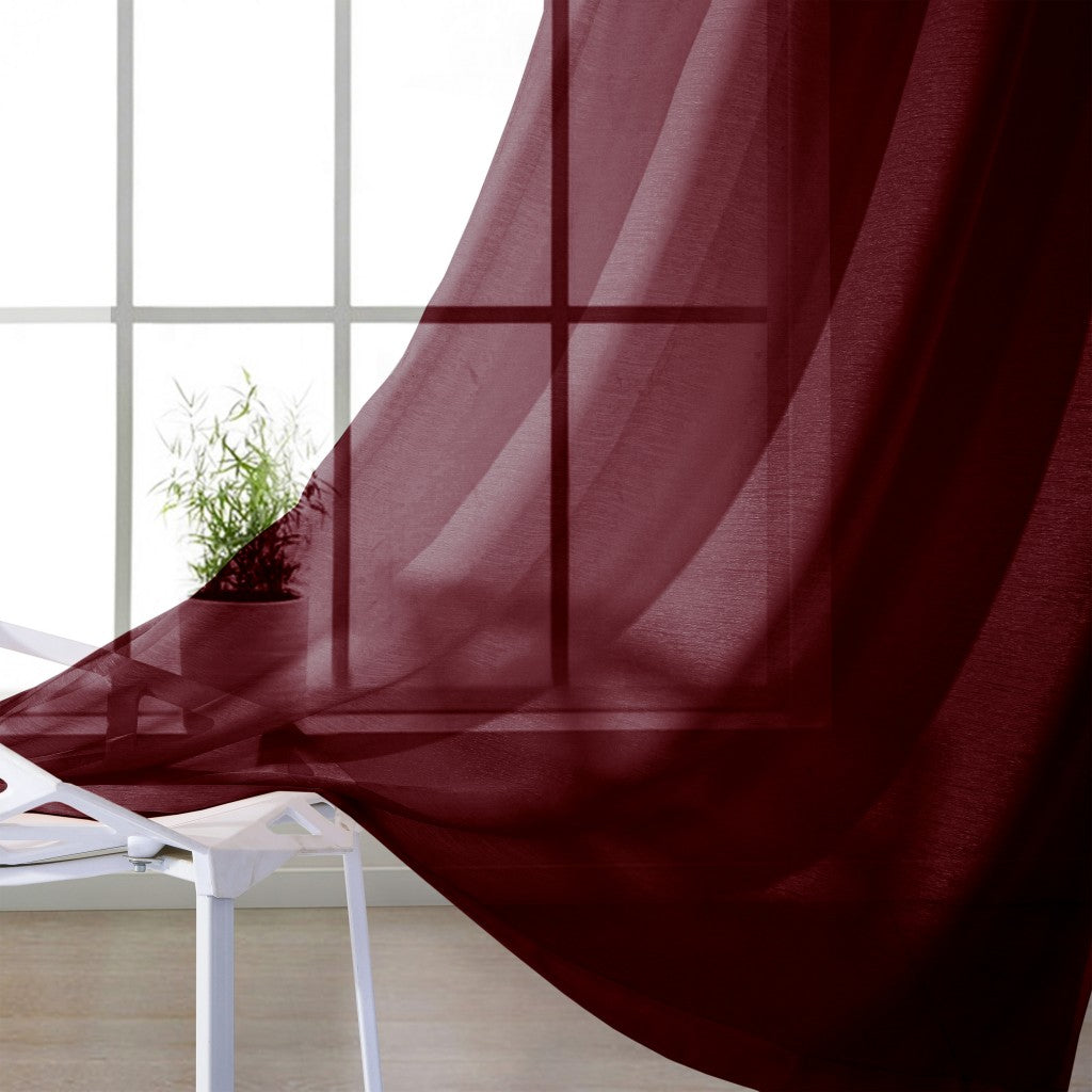 Red curtain partially covering a window with a plant in the background