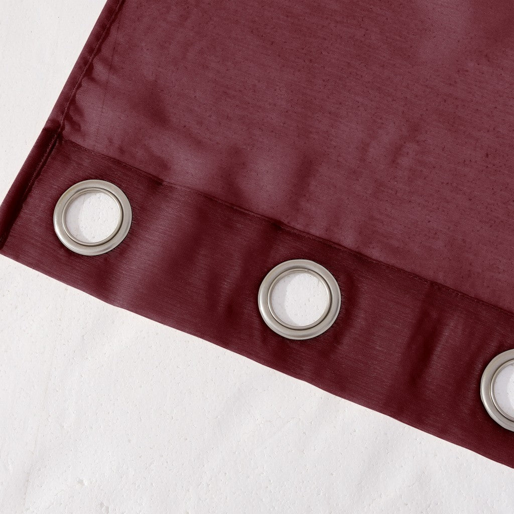Close-up of a burgundy curtain with silver eyelets on a white background