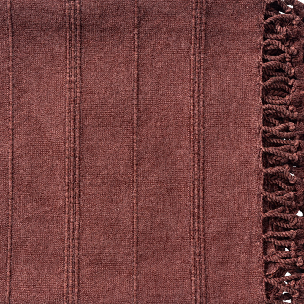 Close-up of a maroon fabric with textured pattern and frayed edge