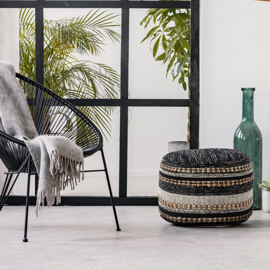 Decorative ottoman with a patterned design in a room with a chair and plants.