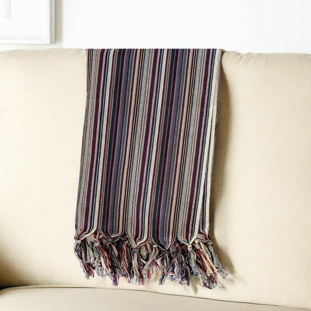 Striped blanket with tassels draped over a beige sofa