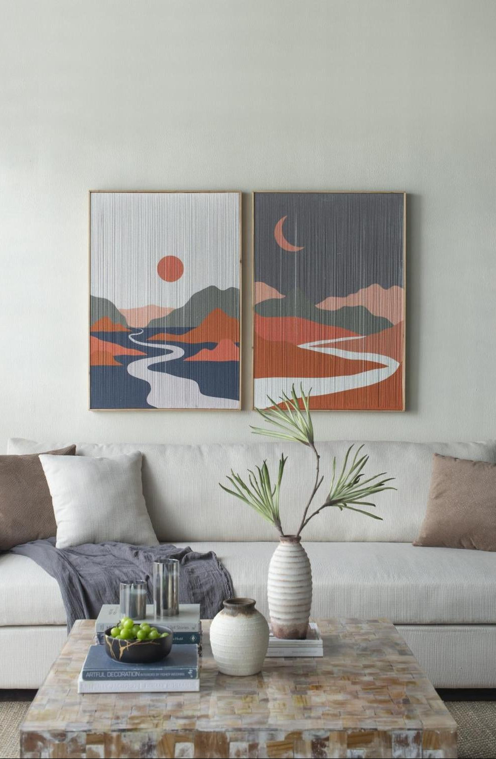 Living room with two abstract landscape paintings on the wall, a white sofa, and a coffee table with decorative items.