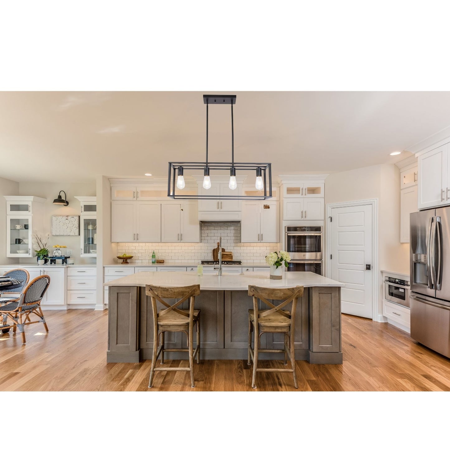 Modern kitchen with stainless steel appliances, wooden island, and chairs.