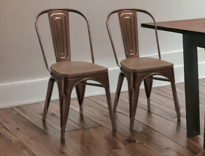 Two brown metal chairs in front of a wooden table on a wooden floor.
