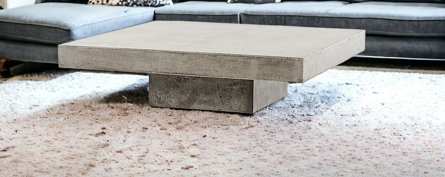 Concrete coffee table in a living room setting with a gray sofa.