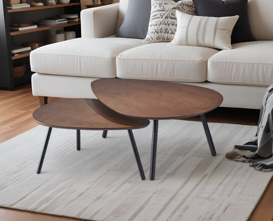 Two wooden coffee tables in front of a white sofa with decorative pillows on a light rug.
