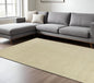 Gray sectional sofa with white cushions on a beige patterned rug in a living room.