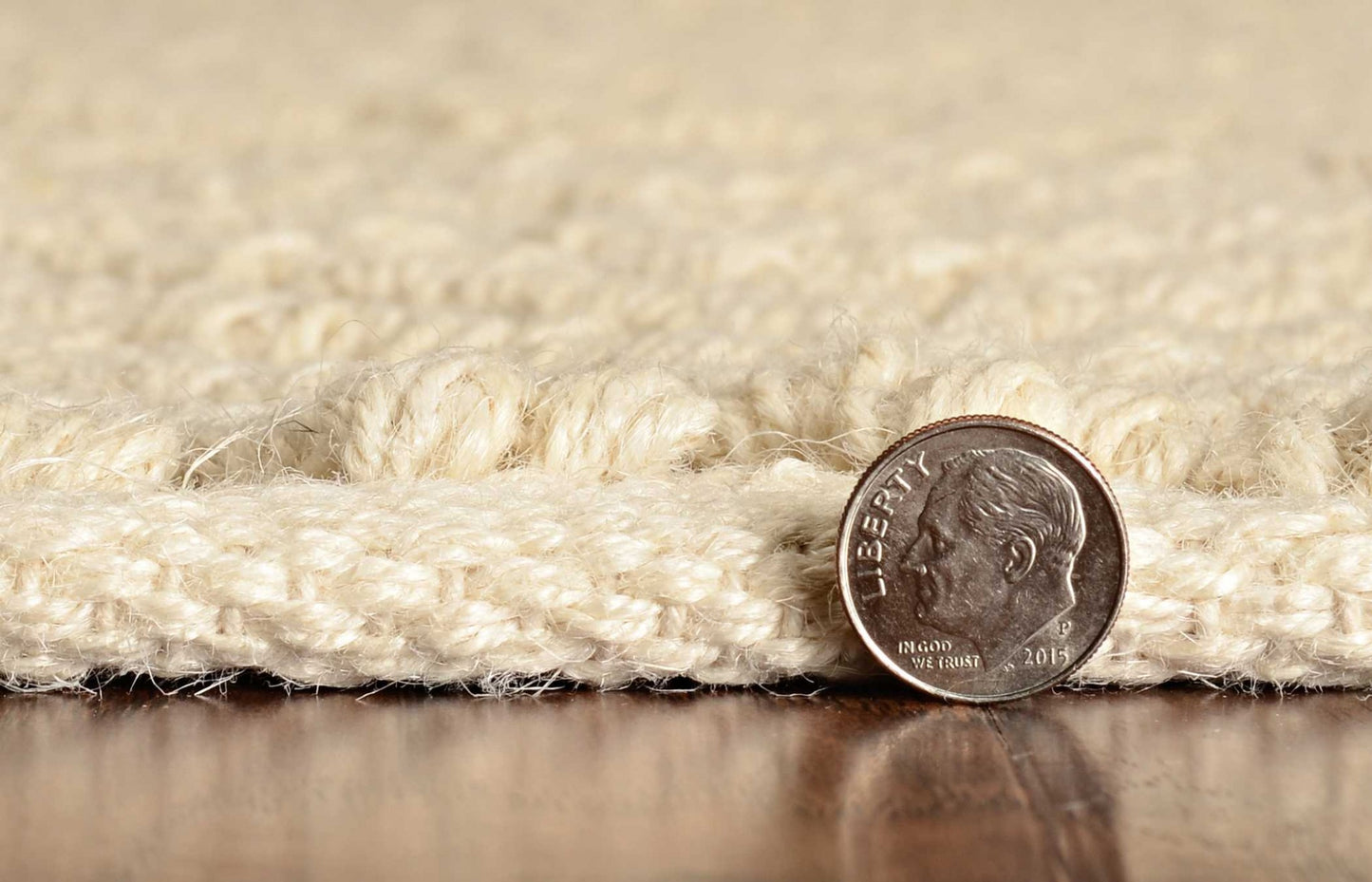 Close-up of a rope with a U.S. quarter coin for scale on a wooden surface.