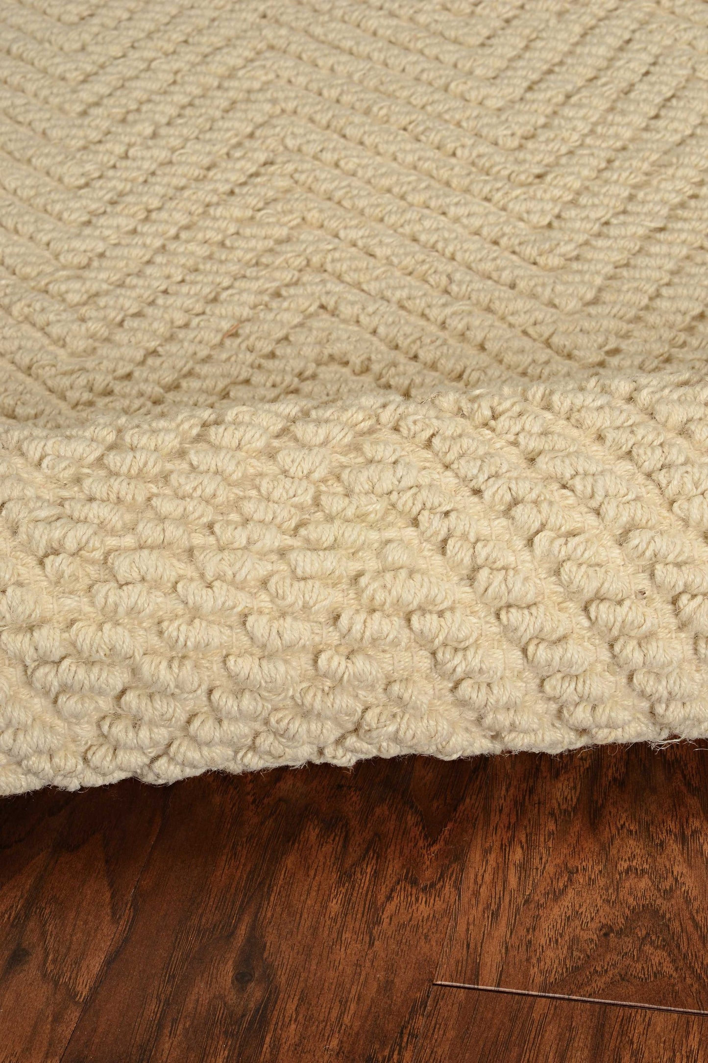 Close-up of a textured beige rug on a wooden floor