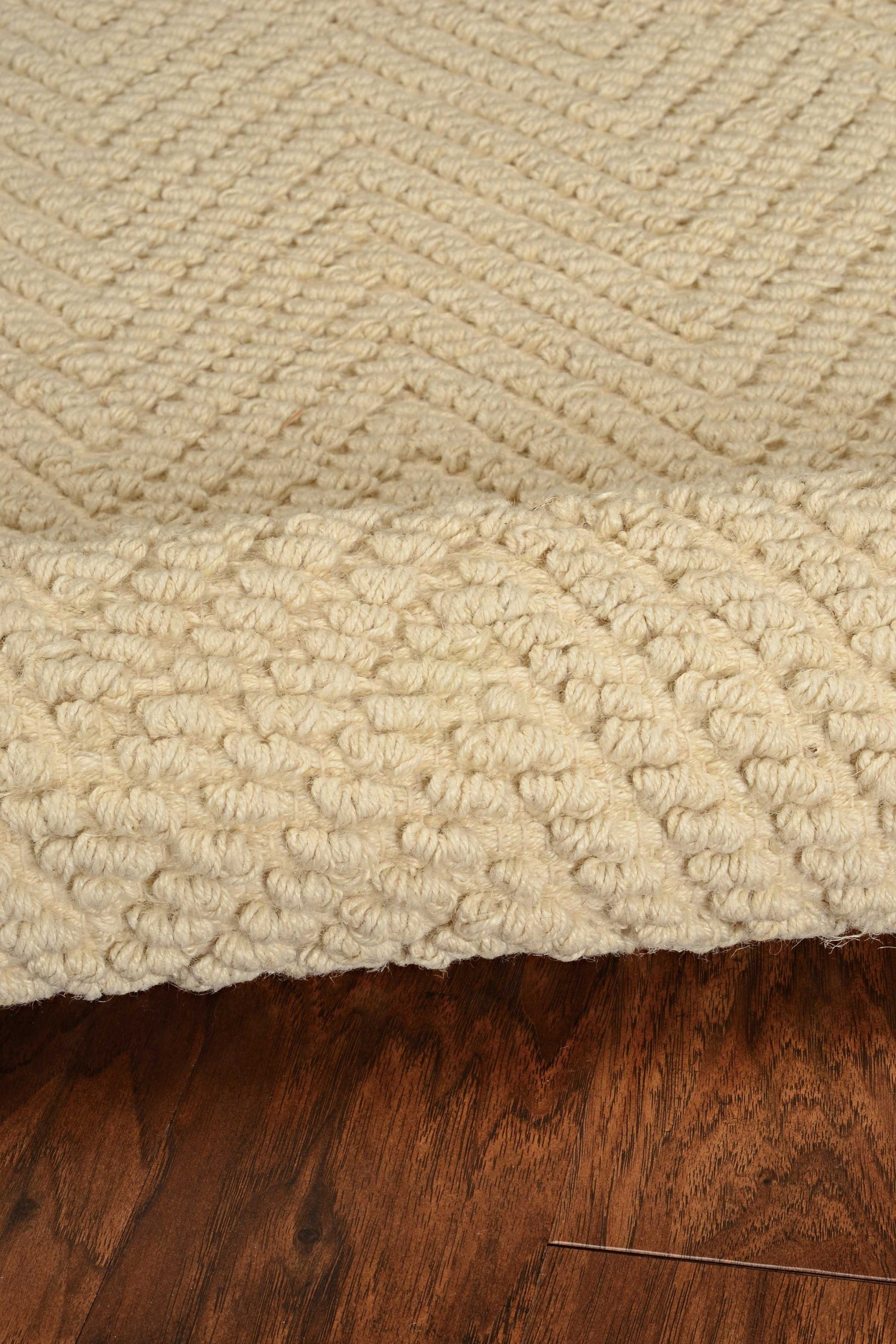 Close-up of a textured beige rug on a wooden floor