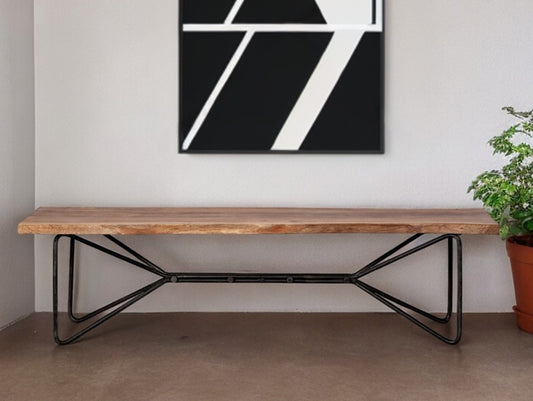 Wooden bench with black metal legs in a room with a abstract art piece on the wall.
