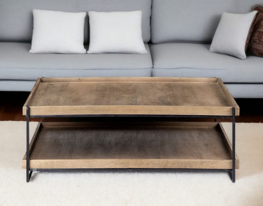 Wooden coffee table with metal frame in front of a gray sofa with white cushions.