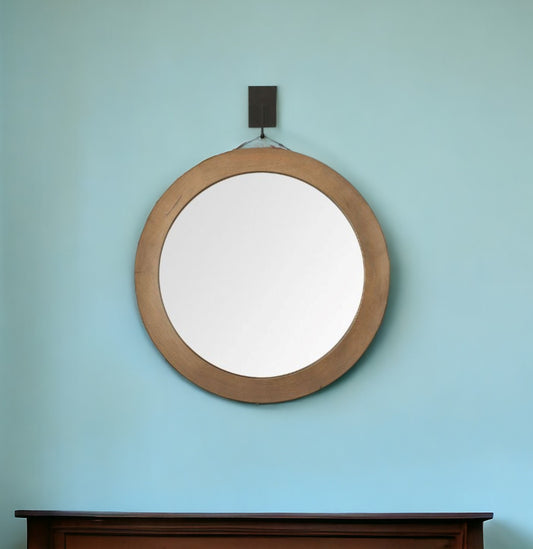 Round wooden-framed mirror on a light blue wall