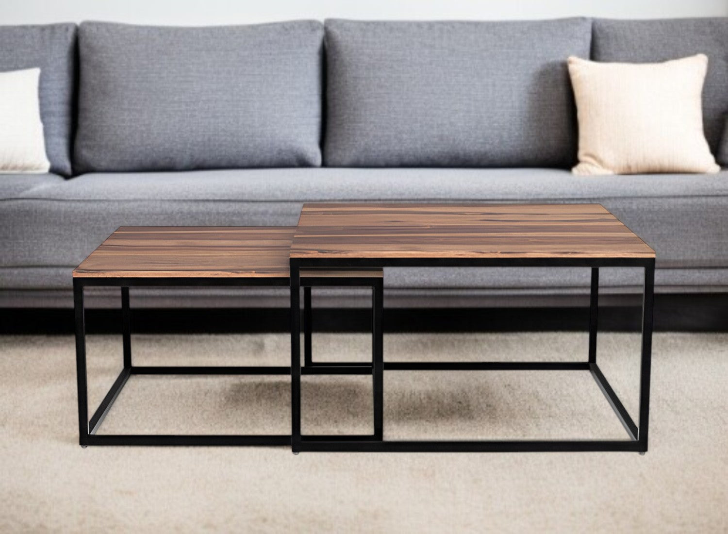 Two wooden coffee tables with metal frames in front of a gray sofa.