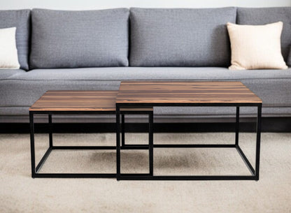Two wooden coffee tables with metal frames in front of a gray sofa.