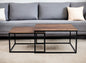 Two wooden coffee tables with metal frames in front of a gray sofa.