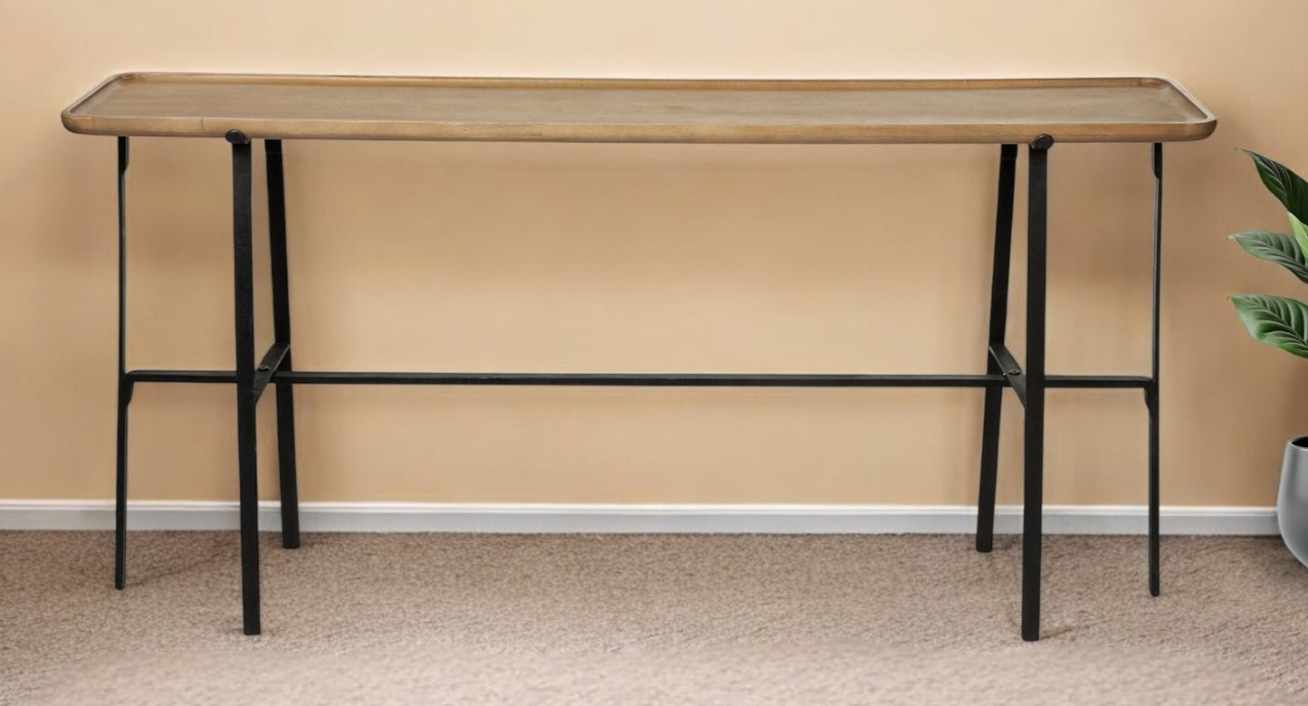 Long wooden table with black metal legs against a beige wall.