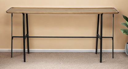 Long wooden table with black metal legs against a beige wall.