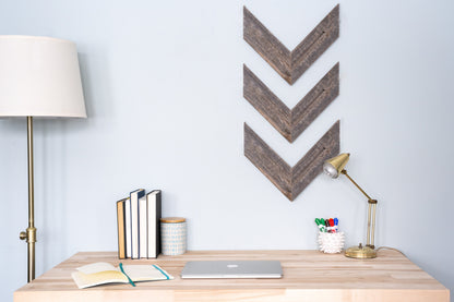 Wooden desk with decorative wall art and office supplies against a light blue wall.