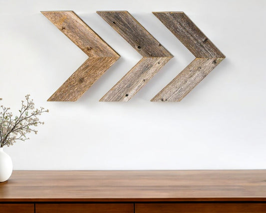 Three wooden arrow-shaped wall decorations on a white wall above a wooden surface.