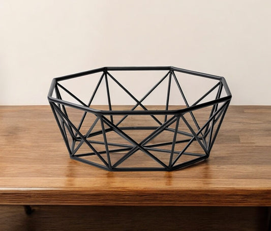 Geometric black metal bowl on a wooden surface with a plain background