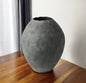 Textured gray vase on a wooden surface with a neutral background