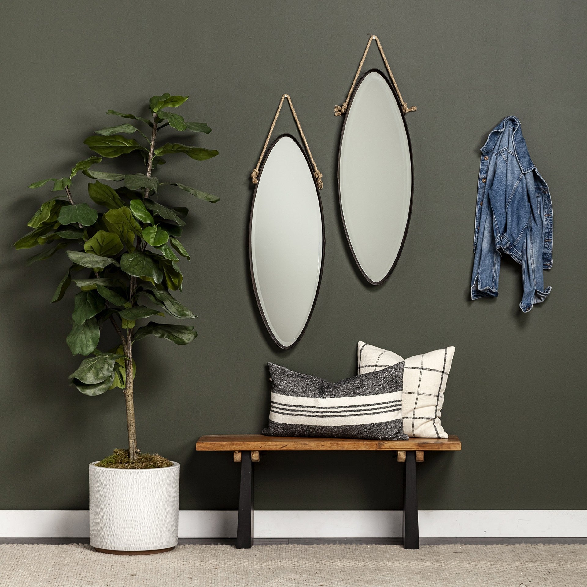Nestled corner with a plant, bench, and wall mirrors on a dark gray wall.