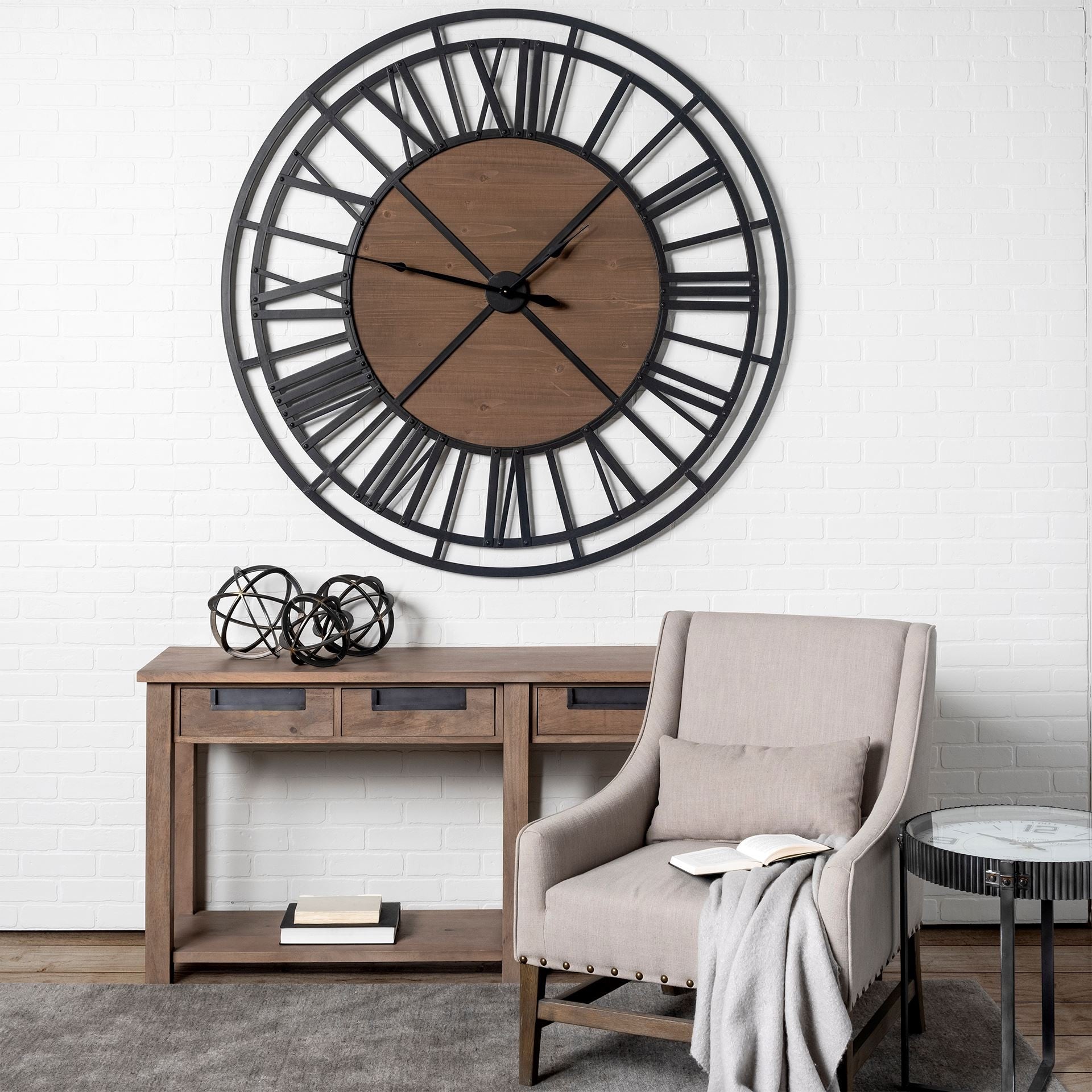 Large wall clock above a wooden console table with a chair and decorative items in a room.