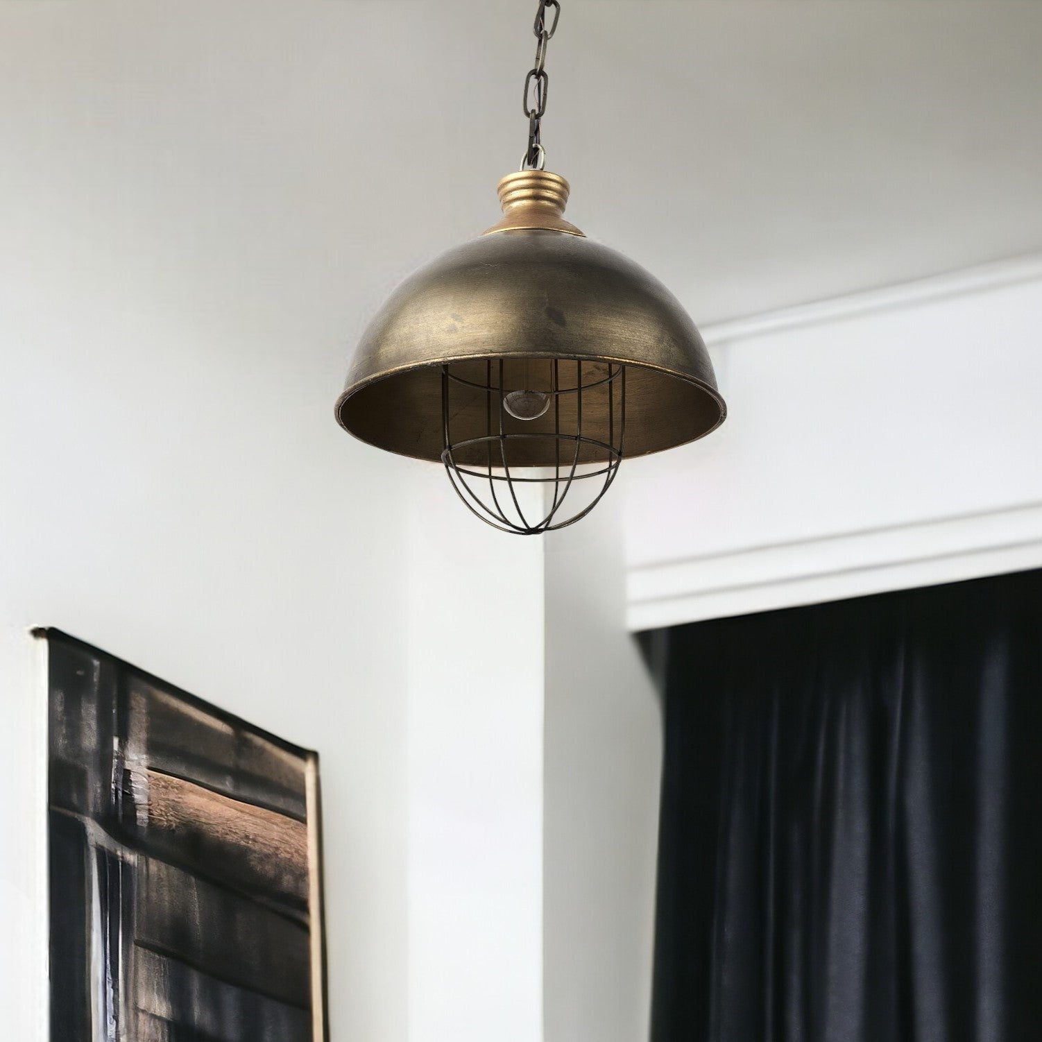 Bronze pendant light hanging in a room with a white wall and black curtain.
