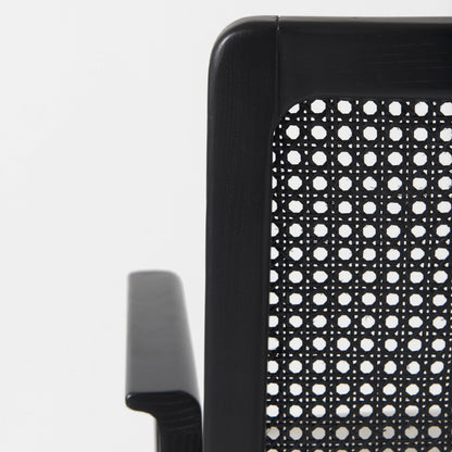 Close-up of a black office chair with a perforated backrest on a white background