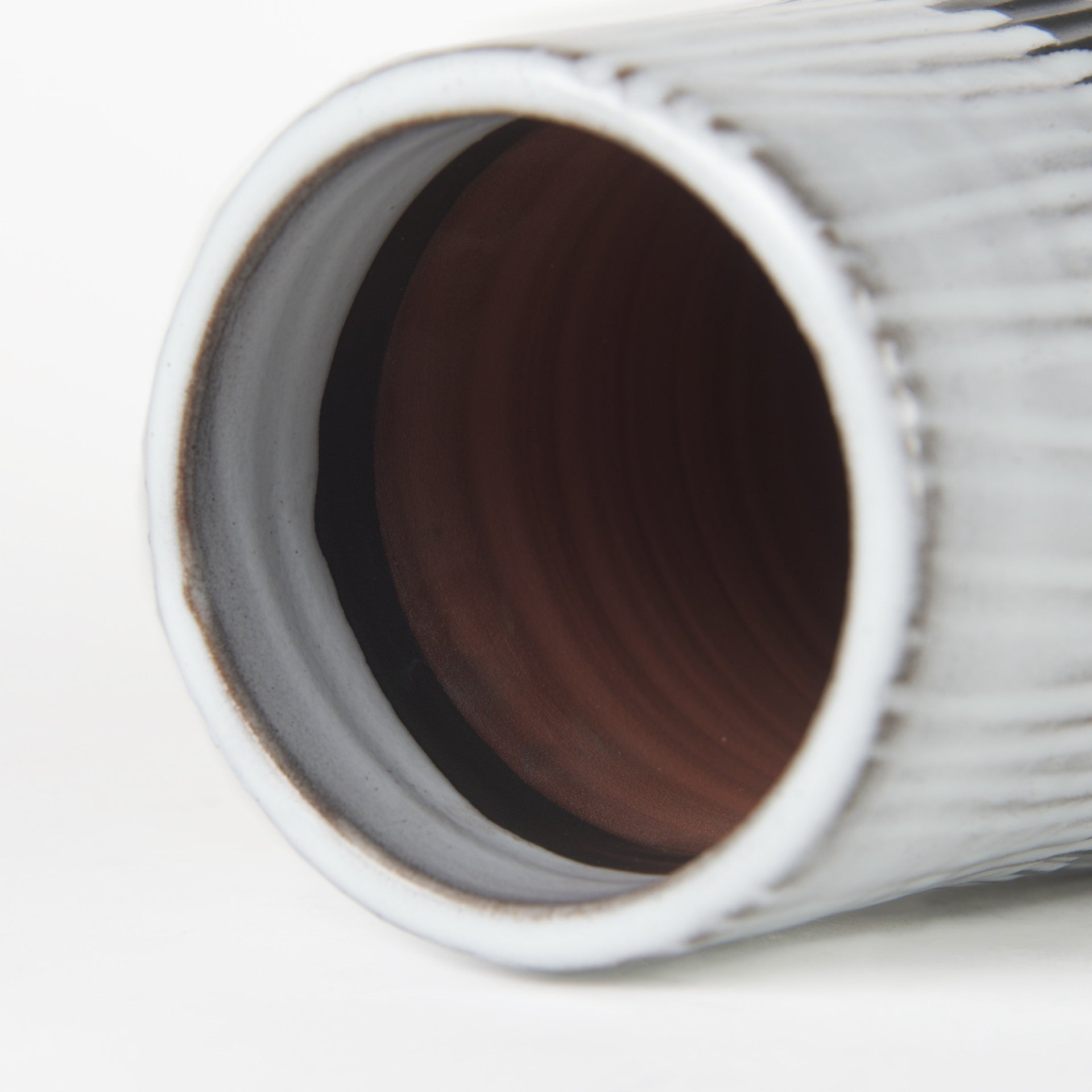 Close-up of a cylindrical vase with a textured surface on a white background