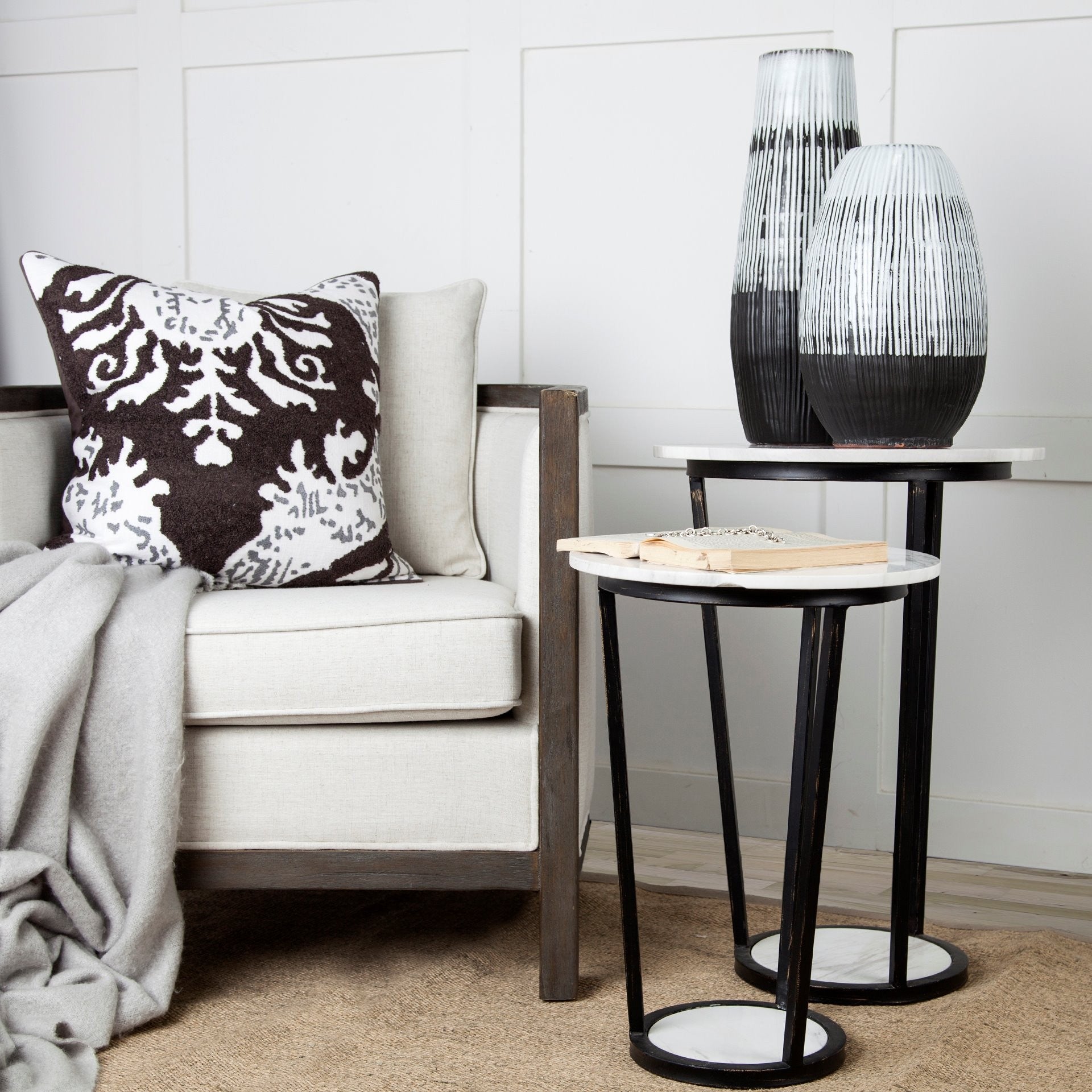 Modern living room with a sofa, decorative pillow, and side tables with vases.